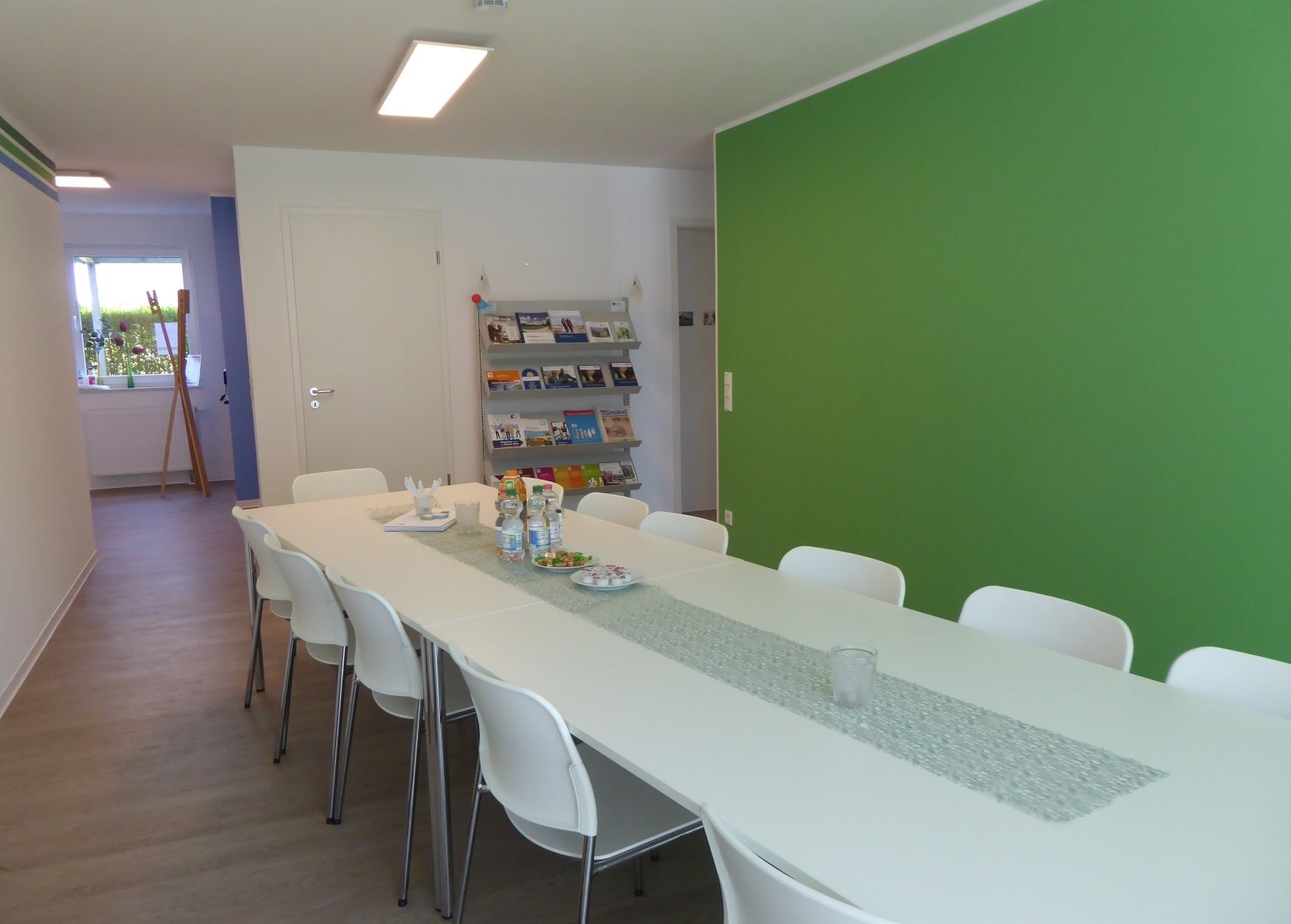 Bildmotiv zeigt einen Innenraum des Seniorentreffs Bullerbach mit einem langen weißen Tisch und Bestuhlung in einem Raum mit weißen und einer grünen Wand
